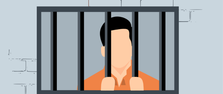 Eine Gefangener in orangen Pullover hinter einem vergitteren Fenster