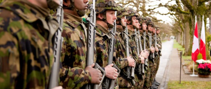 Schweizer Armee verschlingt jährlich 8,5 Milliarden Schweizer Soldaten mit Sturmgewehren vor Schweizer Flaggen