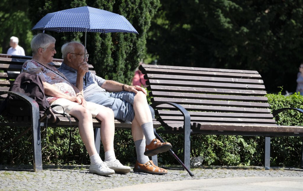 Zwei Pensionäre auf einer Parkbank mit Sonnenschirm