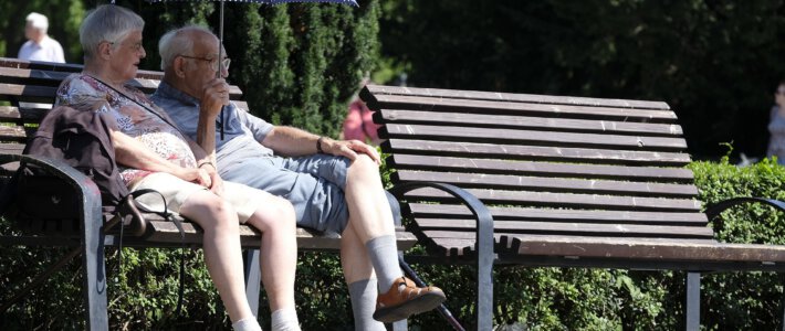 Zwei Pensionäre auf einer Parkbank mit Sonnenschirm