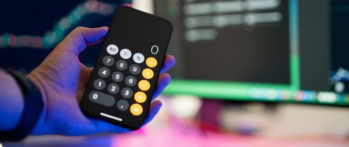 Index verrät Geheimnis hoher Schweizer Preise Ein Taschenrechner in einer Hand vor Bildschirmen