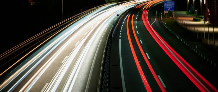 Schweiz verdient sogar Geld mit Strassen Eine Strasse bei Nacht mit Fahrzeuglichtern in Luzern