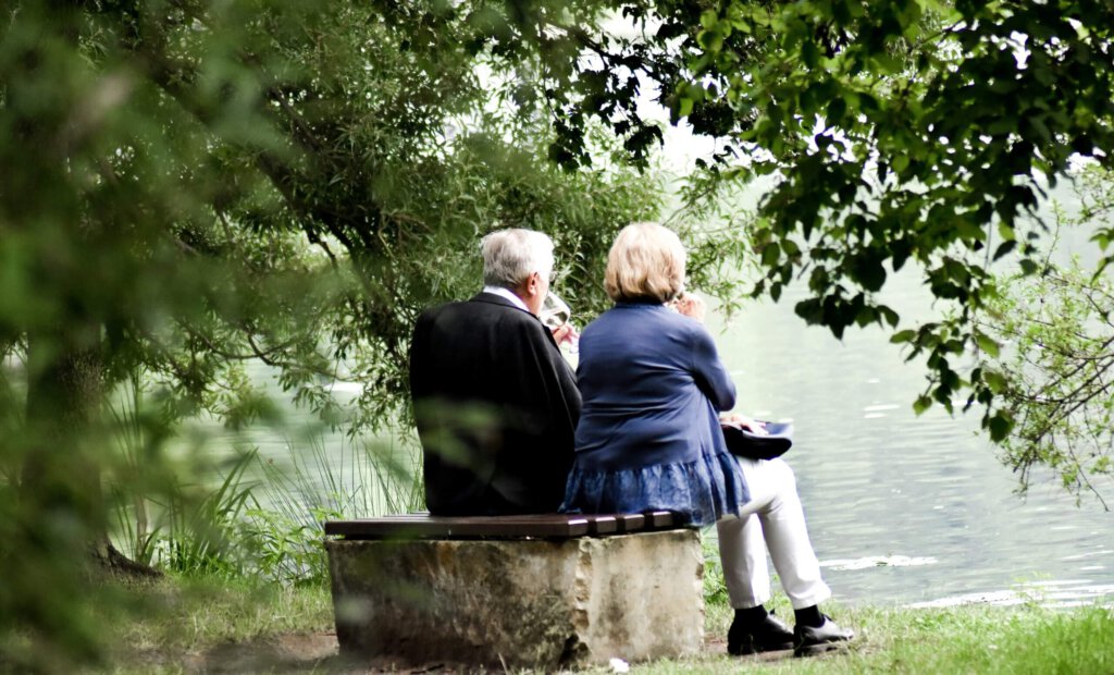 Eine älteres Ehepaar auf einer Bank an einem Teich