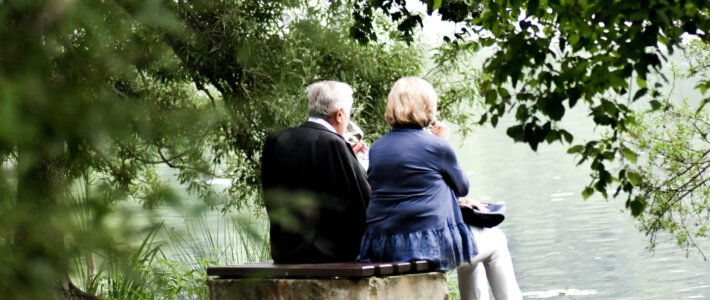 Eine älteres Ehepaar auf einer Bank an einem Teich