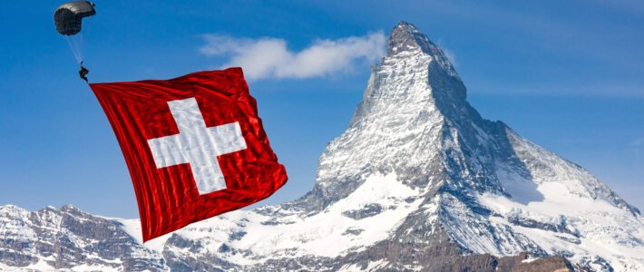 Ein Militärfallschirmspringer mit einer Schweizerfahne vor dem Matterhorn