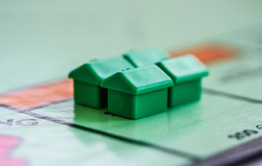 Vier grüne Häuser auf einem Monopoly-Feld