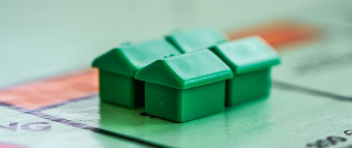 Vier grüne Häuser auf einem Monopoly-Feld