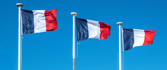 Franzosen überrennen den Schweizer Arbeitsmarkt Drei französische Flaggen an Fahnenmasten