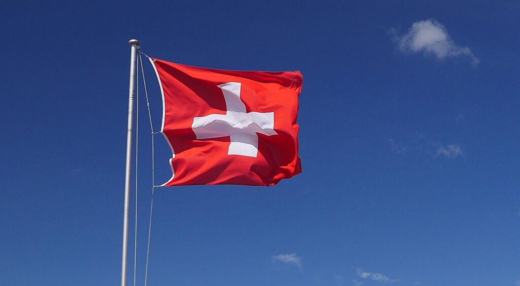 Eine Flagge der Schweiz im Wind vor blauen Himmel