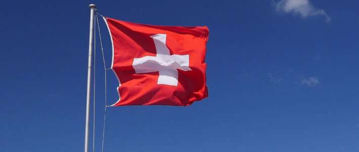 Eine Flagge der Schweiz im Wind vor blauen Himmel