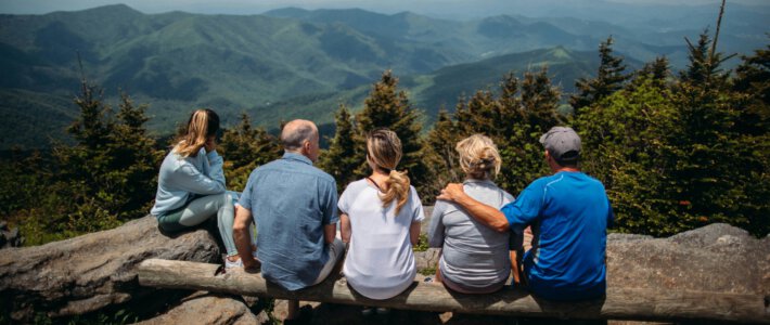 Schweiz missachtet die Generationengerechtigkeit Drei Generationen sitzen auf einer Bank vor Bergen