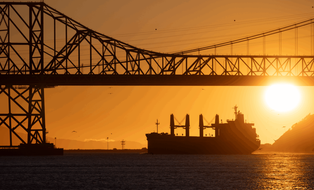 Ein Erdöltanker unter einer Brücke beim Sonnenuntergang