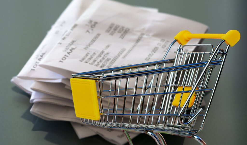 Ein leerer Warenkorb mit Kassenbons dahinter