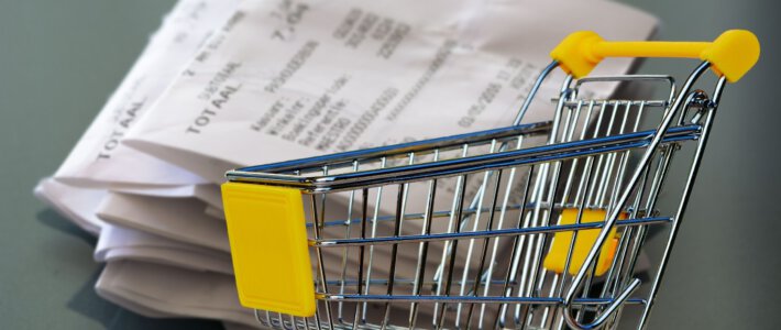 Ein leerer Warenkorb mit Kassenbons dahinter