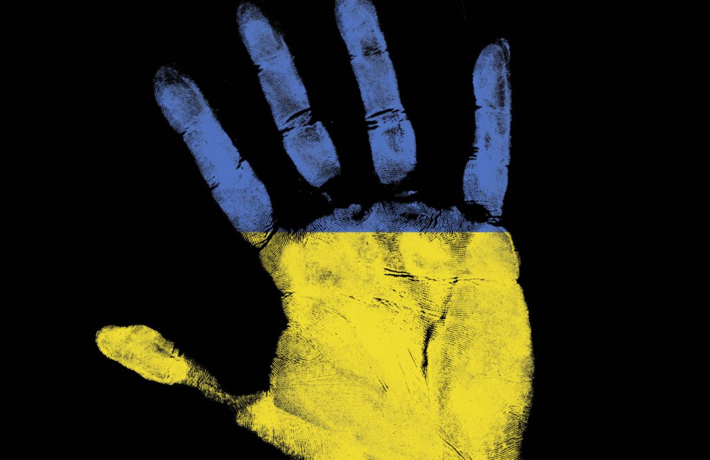 Eine Hand in den Farben der Ukraine vor schwarzem Hintergrund