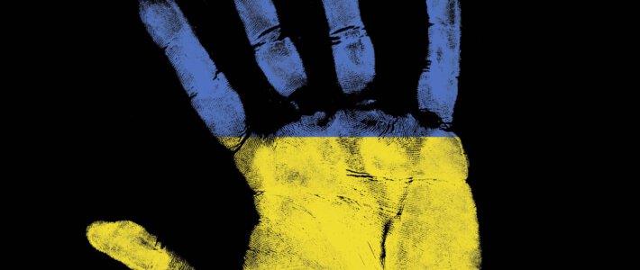 Eine Hand in den Farben der Ukraine vor schwarzem Hintergrund
