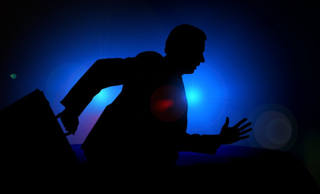 Ein Manager mit Aktenkoffer vor Blaulicht der Polizei