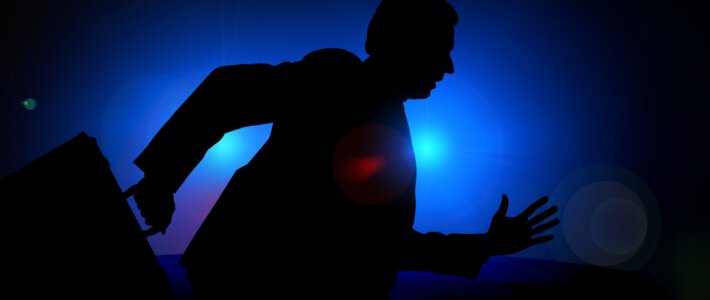 Ein Manager mit Aktenkoffer vor Blaulicht der Polizei