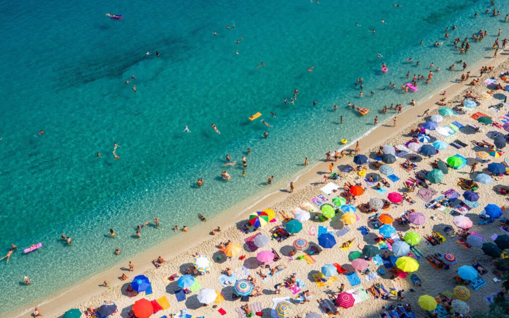 Menschen am Strand mit Sonnenschirmen