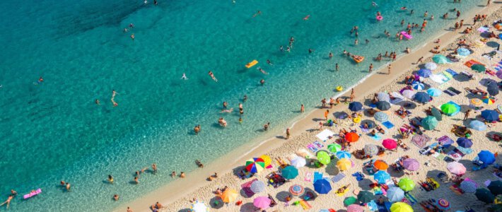 Menschen am Strand mit Sonnenschirmen