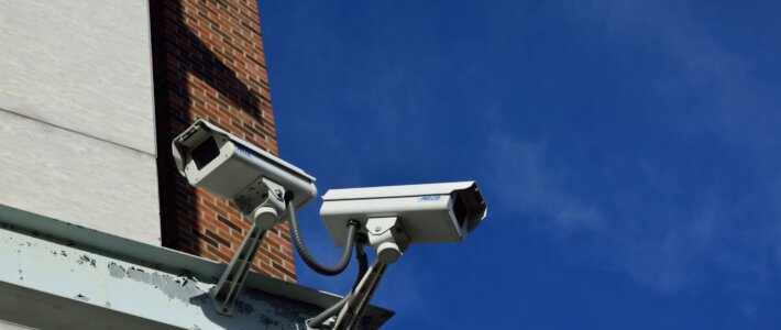 Schweiz weitet Schnüffelstaat nochmals deutlich aus CCTV-Kameras an einem Gebäude vor blauem Himmel