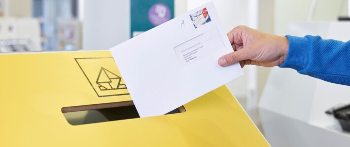 Ein A-Post-Brief wird in einen Briefkasten geworfen