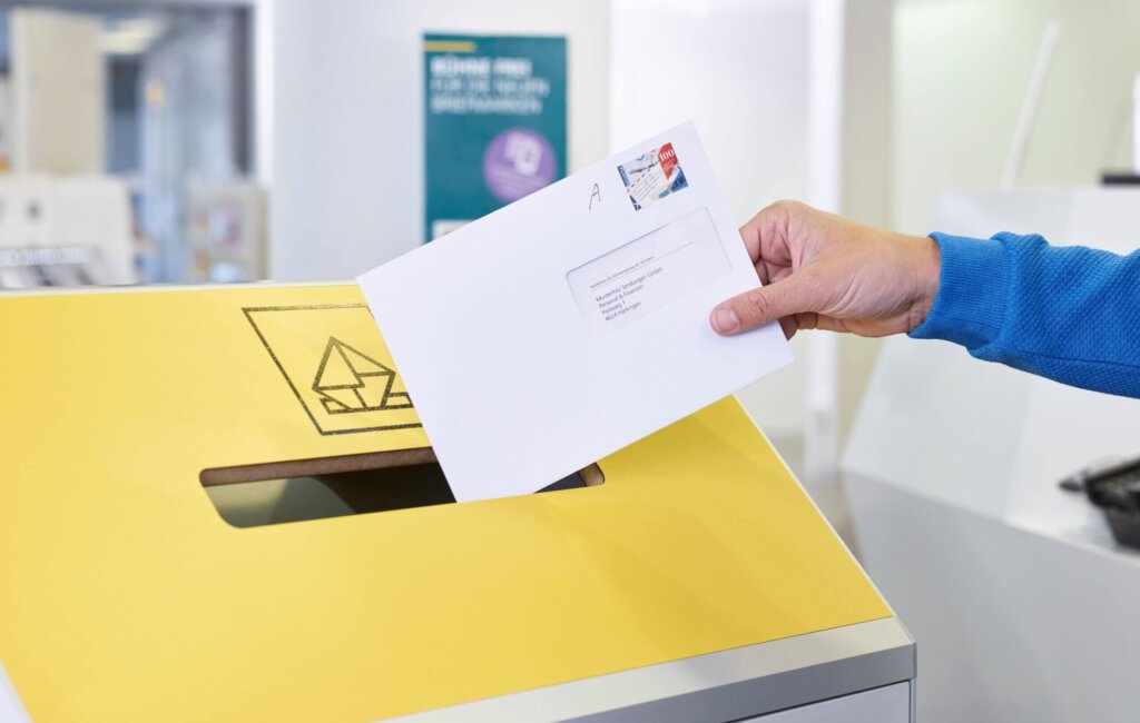 Ein A-Post-Brief wird in einen Briefkasten geworfen