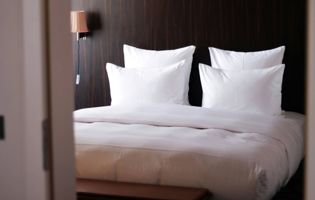 Ein Hotelbett mit Kissen und Holzverkleidung an der Kopfseite