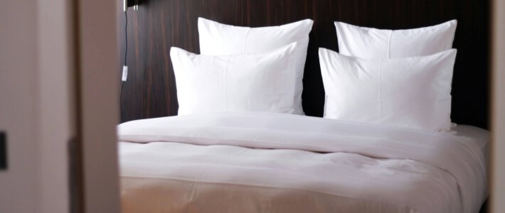 Hotels auf der Suche nach Golfarabern und Indern Ein Hotelbett mit Kissen und Holzverkleidung an der Kopfseite