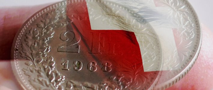 Erhebliche Mehrbelastungen bei Bürgern und Firmen Eine Schweizer Flagge mit einer 2-Franken-Münze