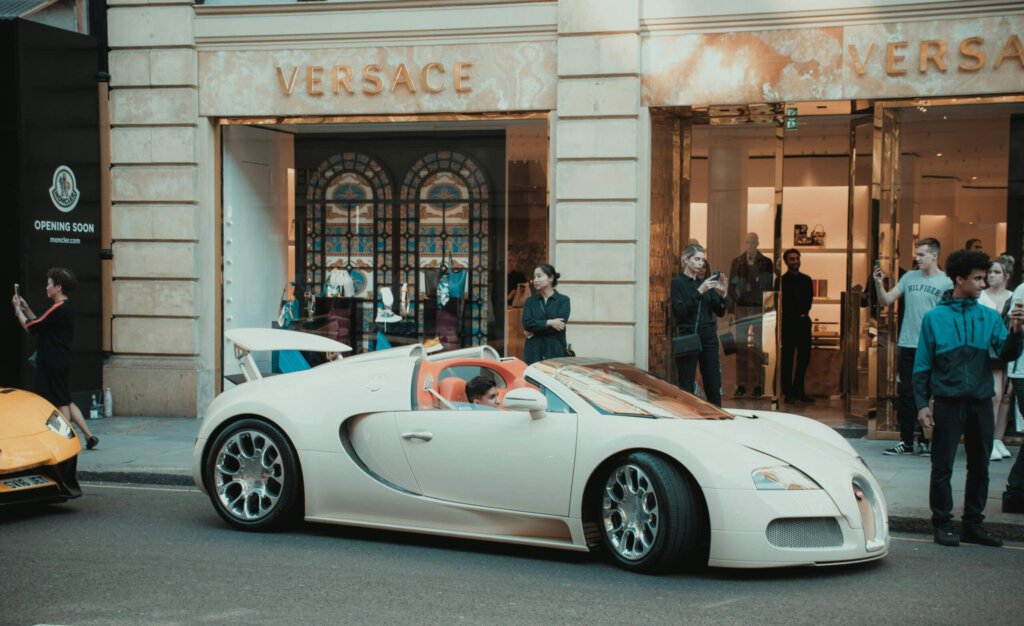 Ein Knabe in einem Luxusauto vor einer Nobelboutique