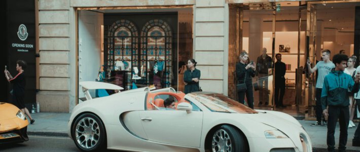 Jeden Tag über 2600 neue Millionäre Ein Knabe in einem Luxusauto vor einer Nobelboutique