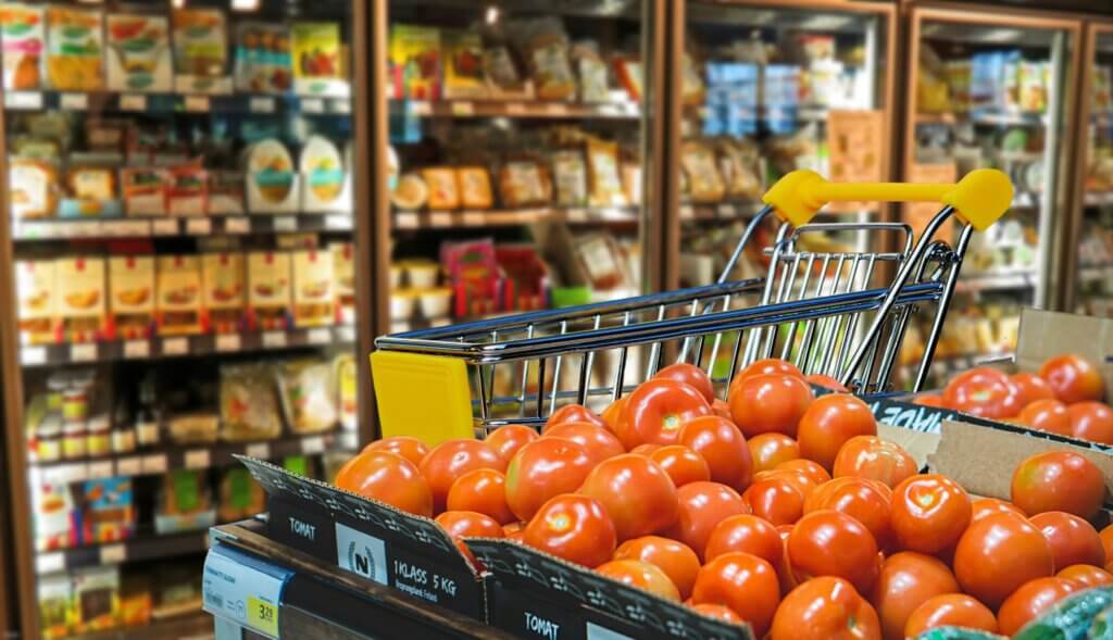 Ein Supermarkt mit Warenkorb und Tomaten im Vordergrund