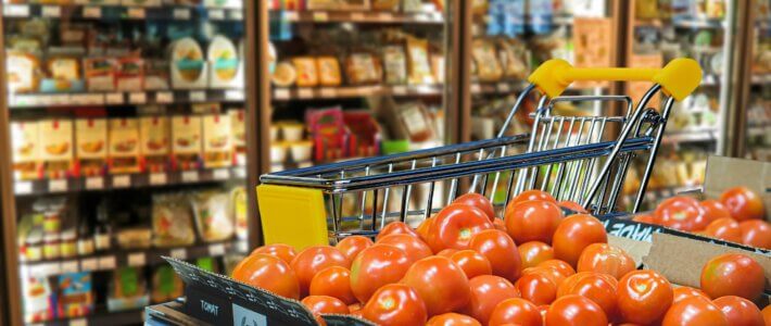 Teuerung schnellt in die Höhe Ein Supermarkt mit Warenkorb und Tomaten im Vordergrund