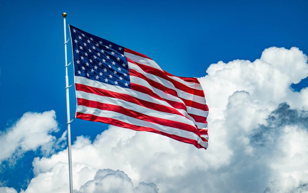 Eine US-Flagge im Wind vor blauem Himmel mit weissen Wolken