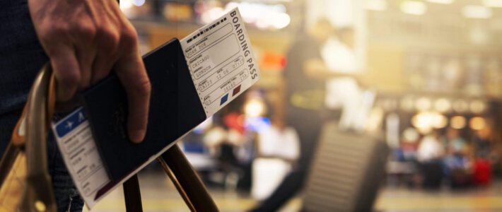 Volumen- und Umsatzdivergenz bei Geschäftsreisen Eine Person mit einem Flugticket in einem Reisepass an einem Flughafen